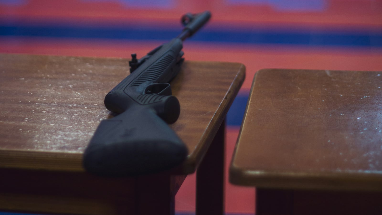 Carabine .22LR posée sur un banc en bois dans un stand de tir intérieur