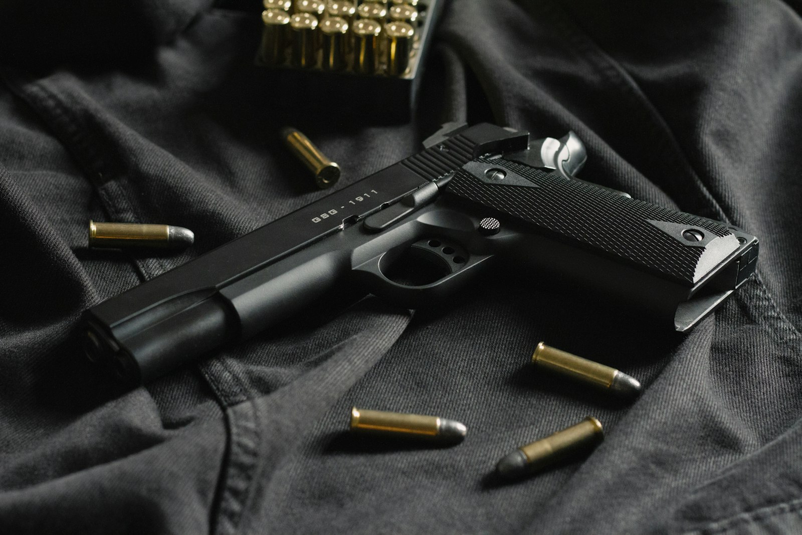 Pistolet semi-auto noir sur tissu sombre, vue de profil