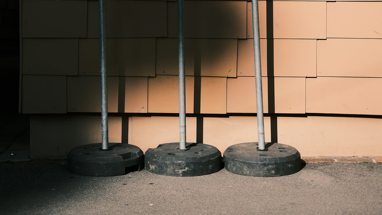 Three steel reactive targets (grey round, rectangular, yellow round) mounted on weighted stands against a wall, shooting range