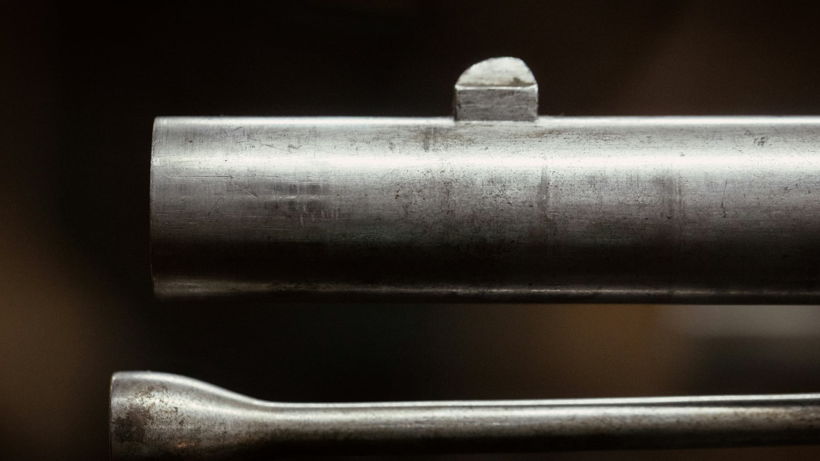 Macro close-up of a firearm barrel and a metal cleaning rod