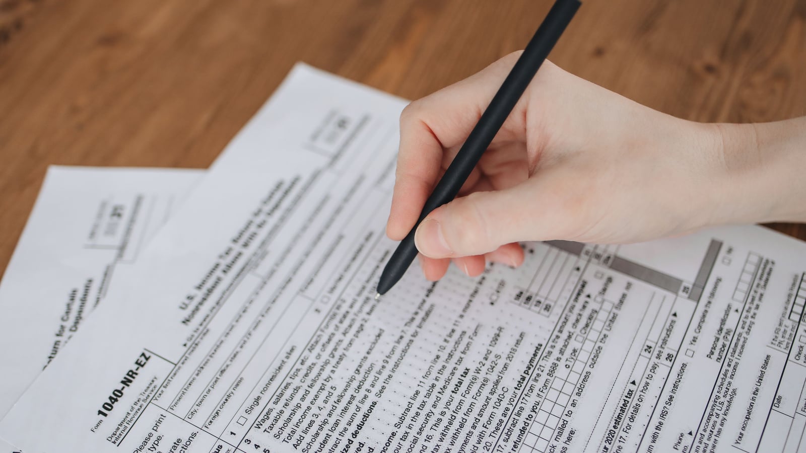 Hand filling out an administrative form with a pen, close-up on the documents